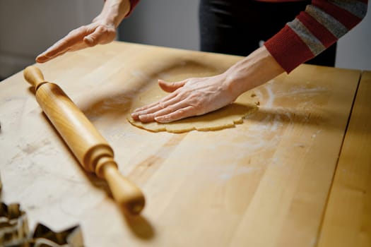 Unrecognizable woman rolls out dough to make ginger cookies