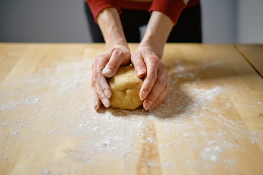 Unrecognizable woman kneads dough with her hands on the table