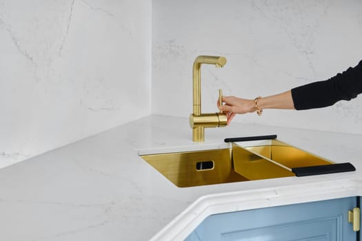 Female hand turns on the water in the sink in the kitchen. Concept of sudden water shutdown