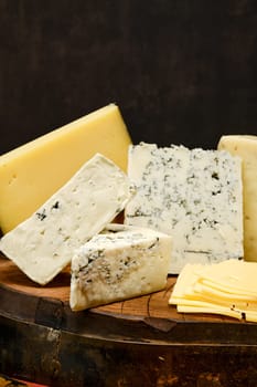 Assortment of different types of cheese on wooden block, closeup view