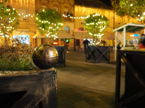 Hanging garlands against the background of the night sky. Festive decoration of city streets. Garlands of yellow, white and gold lights and bulbs. Beautiful background for New Year, Christmas holiday