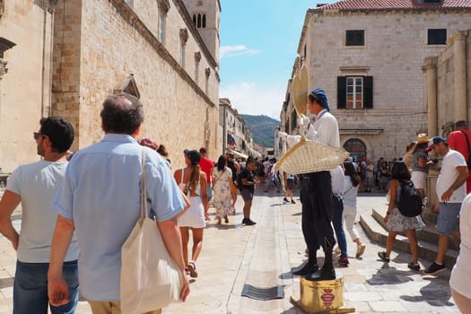 On the streets of Dubrovnik Croatia, happy vacationers walk and buy souvenirs from the seller in the national festive Croatian costume on August 15, 2022. Tourism industry. Summer day. Sale of goods.