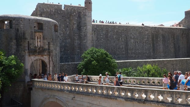 Pile Gate Dubrovnik Croatia August 14 2022 People men and women walk along the stone bridge to the gate of the Old City. Crowd of tourists. Busy entrance. The main entrance to Old Town, busy Pile Gate