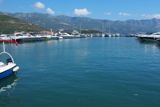 Budva, Montenegro, August 15 2022 Adriatic sea, coast, mountains, sea ripples. Boats and ships are moored to the embankment. Water transport parking. Summer resort trips with tourist water activities.