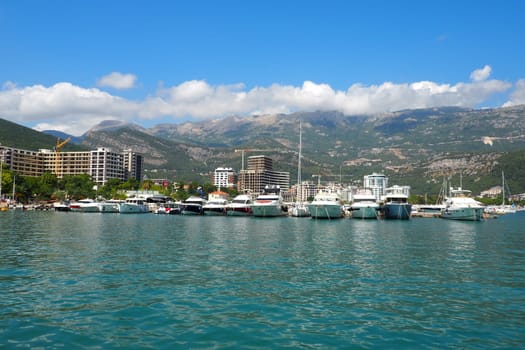 Budva, Montenegro, August 15 2022 Adriatic sea, coast, mountains, sea ripples. Boats and ships are moored to the embankment. Water transport parking. Summer resort trips with tourist water activities.
