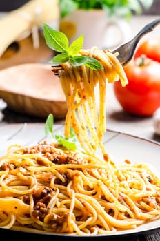 Closeup of italian spaghetti bolognese with basil serve on plate. Traditional homemade italian food recipe. Cooking and gastronomy concept.