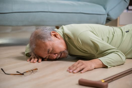 Asian elderly man retired headache after fall down, Sick senior old man falling down lying on floor at house alone with wooden cane walking stick in living room, Health care and medicine concept