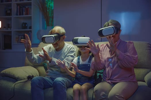 Asian granddaughter and grandparents playing together exciting interesting video games using virtual reality headsets living room at home, elderly with child play VR video game, family entertainment