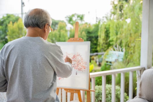 Lifestyle artist. Senior old man painting picture artwork using brush and water color on canvas, portrait elderly white haired paint at his easel outside green nature, Happy retirement and activity
