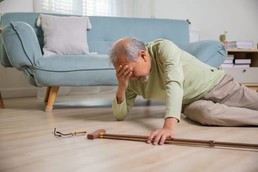 Sick senior old man falling down lying on the ground because stumbled at home alone with wooden walking stick in living room, elderly man grandfather having accident while walk with cane walker