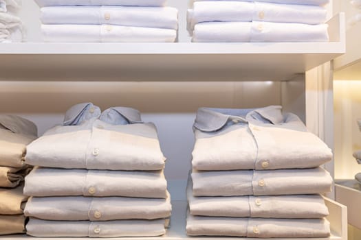 Shelves with colorful shirts neatly folded in clothes store.