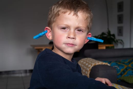 a funny boy with clothes pegs on the ears