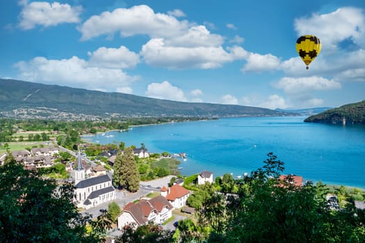 a yellow hot air balloon flying over Annecy lake in the morning, France