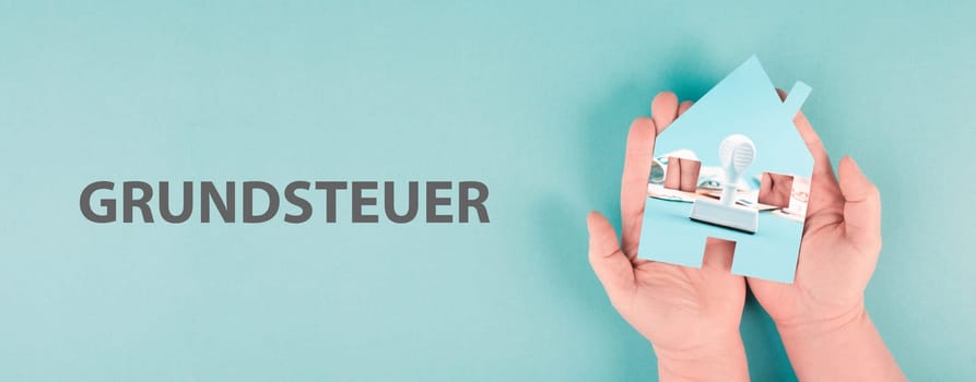 Holding a house in the hand with Euro banknotes and a stamp, new law for property tax, german language
