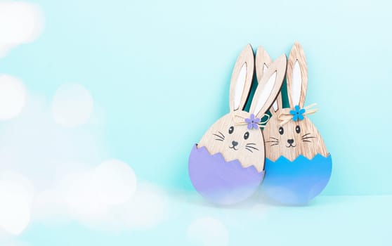 Easter bunny or rabbit couple cuddle together, wooden egg, spring holiday greeting card, bokeh fairy light, blue and purple color