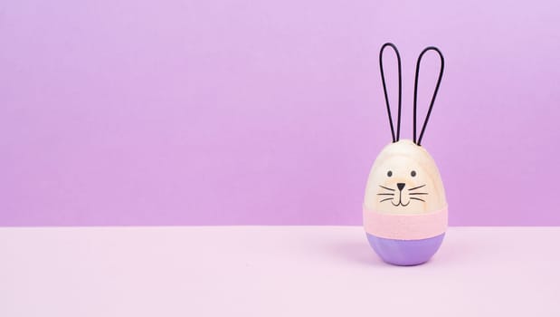 Easter bunny or rabbit, pink holiday background and greeting card, painted wooden egg