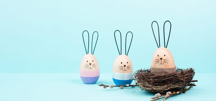 Easter bunny or rabbit group with wicker basket, willow branches, wooden egg, spring holiday greetings