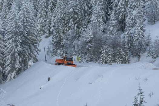 Snow plow truck cleaning snowy road in snowstorm. Snowfall on the driveway.