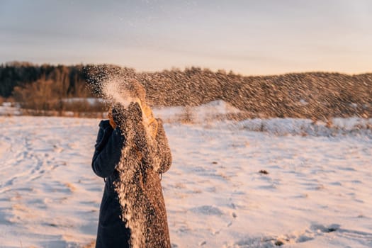 An unidentified woman throws snow in a snow-covered field.