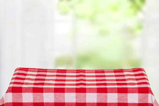 Empty table product. Closeup of a empty red checkered tablecloth or napkin on a rustic table against blurred curtains background. Template for food and product display montage.