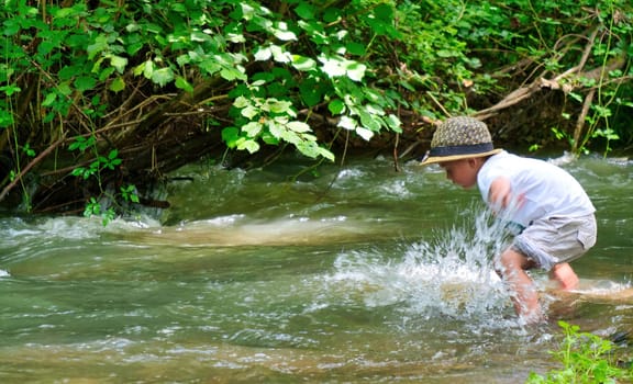 young boy playing in the river