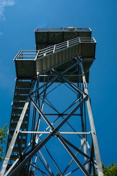 The metal tower in the forest. Blue sky background.