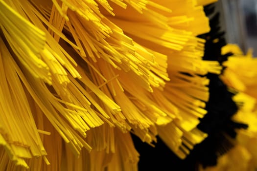 front view closeup detail of black and yellow automatic car wash system cleaning fiber sponge brushes on spinning rotor