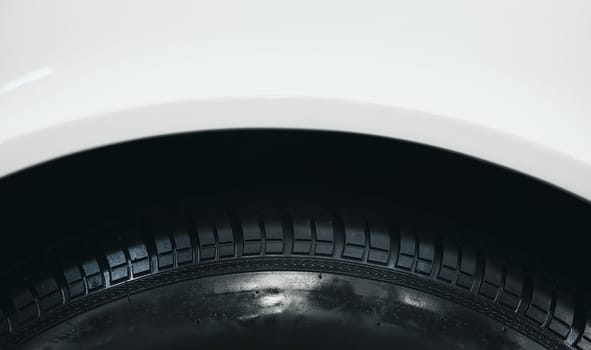 front view detail of car wheel black rubber tire on the front wing fender of white car