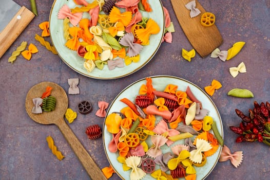 Colorful italian raw pasta on plate. Heap of colorful macaroni