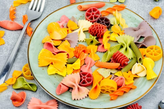 Colorful italian raw pasta on plate. Heap of colorful macaroni