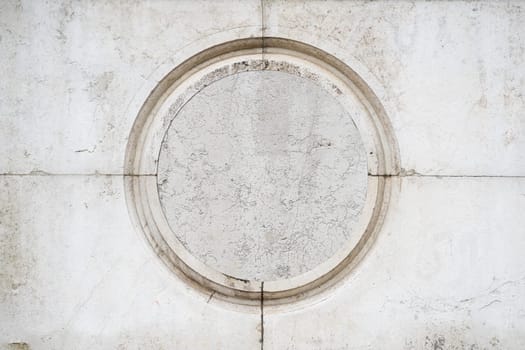 front view closeup of round empty classic ornamental frame signboard plaque on white marble stone wall