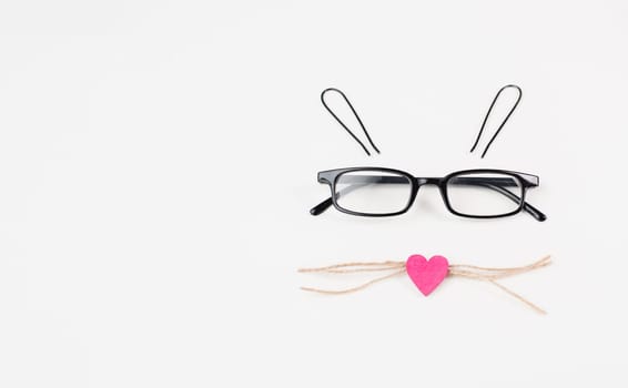Easter bunny face with a heart shaped nose, eyeglasses and whiskers from strings, holiday greeting card, spring season