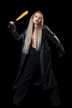 a woman in a black raincoat on a black background with a bat in her hand makes a furious swing. High quality photo