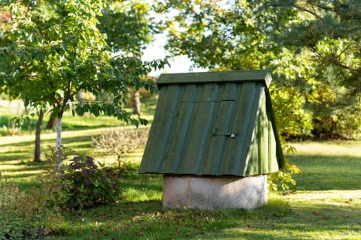 Old well with water, covered with green old planks in a garden plot
