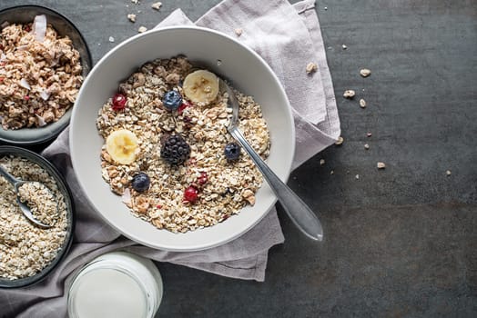 A bowl of muesli served with fresh fruit nuts and milk. Oatmeal plate. Healthy food, diet. Top view.