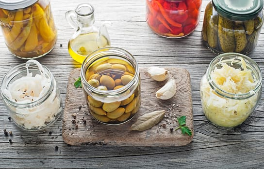 Canned and pickled vegetables in glass jars on wooden table. Preserved food