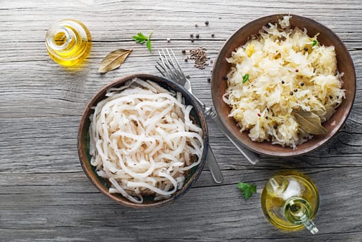 Traditional healthy sauerkraut and sour turnip on wooden background.