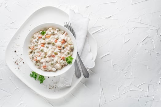 Bowl of russian salad olivier french salad with vegetables and egg dressed with mayonnaise on white table