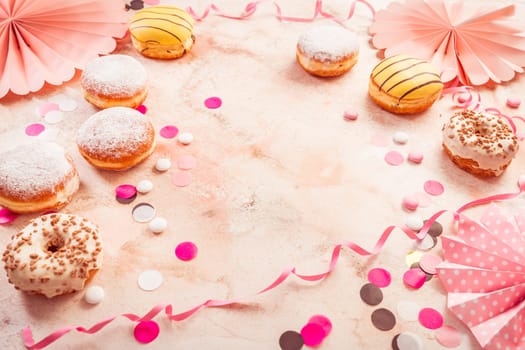 Traditional Berliner for carnival and party. German Krapfen or donuts with streamers and confetti. Colorful carnival or birthday image