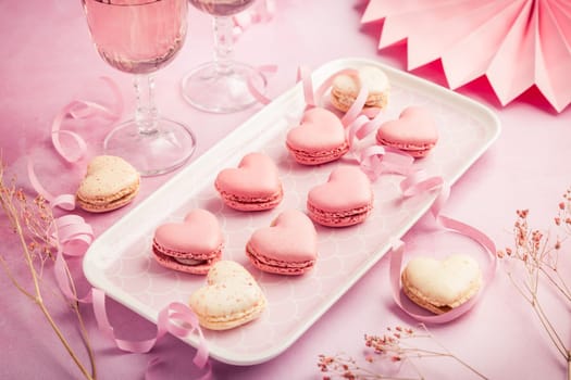 Happy Mothers Day, Happy Valentine - sweet macarons in heart shape and glasses of rose sparkling wine in pink tone