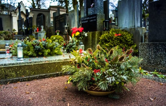 Flower arrangement and funeral wreath at grave in cemetery. Tombstones and a chapel in the public cemetery. Grief and paying respect for dead person. T