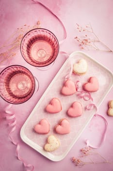 Happy Mothers Day, Happy Valentine - sweet macarons in heart shape and glasses of rose sparkling wine in pink tone
