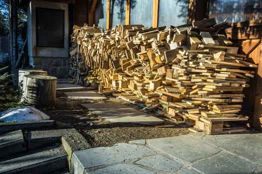 A pile of stacked firewood, prepared for heating the house, harvested for heating in winter on the house wall