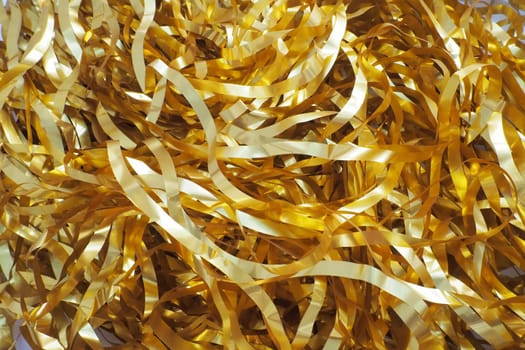Tinsel-rain of golden color. New Year and Christmas decorations for the Christmas tree, interior or party room. Weaving threads of golden foil. Festive beautiful shiny background. Tinsel close-up.