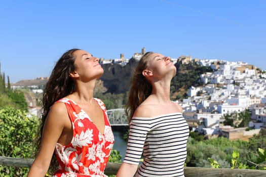 Two relaxed friends on summer vacation breathing fresh air