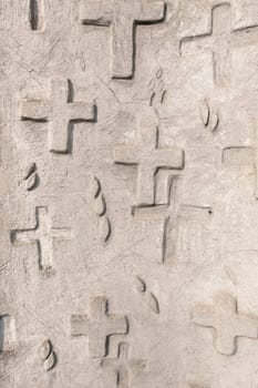 Abstract background of engraved and relief crosses on stone wall. Religious symbol.