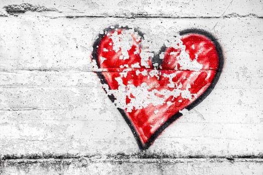 Painted red abstract heart shape love symbol, dirty wall background, metaphor to urban and romantic valentine, grunge style.