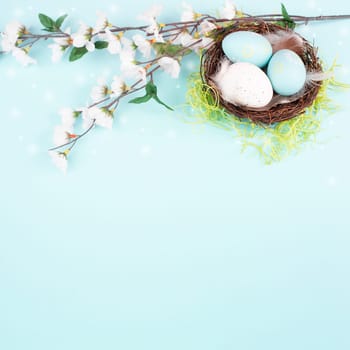 Colored easter eggs in a bird nest, pink cherry blossoms, green grass, holiday greeting card, spring season background