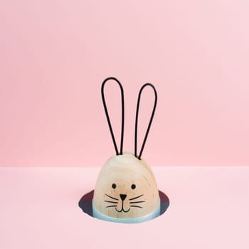Easter bunny or rabbit peeking out a hole, spring holiday greeting card, pink pastel color, minimailism