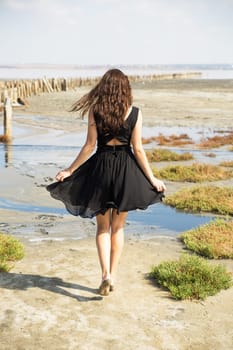 A young slender girl walks along the sandy bottom, during the low tide of the sea - Kuyalnik Odessa Ukraine.
